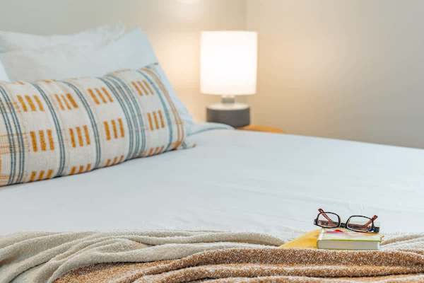 Queen-size bed in the second bedroom with bedside lamp.