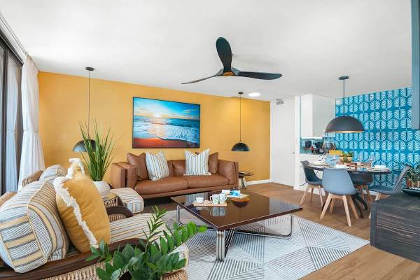 Living room with comfortable sofa, coffee table, ceiling fan, and 2 armchairs.