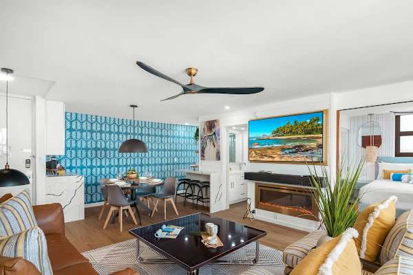 Living room with comfortable sofa, coffee table, ceiling fan, and 2 armchairs. Plus, a 65'' Smart TV.