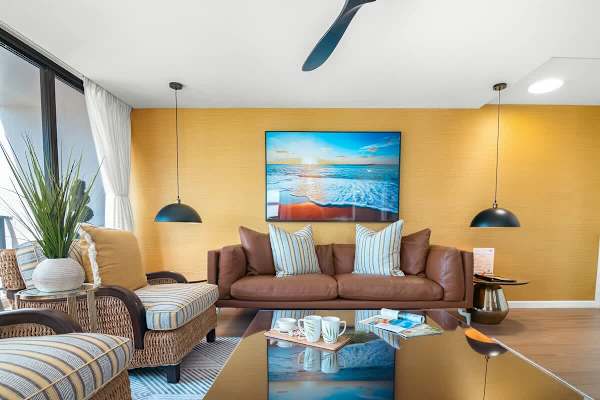 Living room with comfortable sofa, coffee table, ceiling fan, and 2 armchairs.
