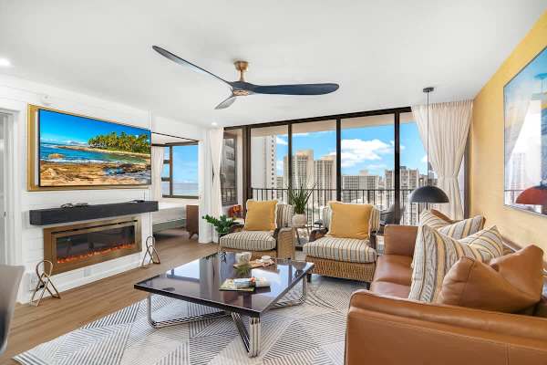 Living room with comfortable sofa, coffee table, ceiling fan, and 2 armchairs. Plus, a 65'' Smart TV.