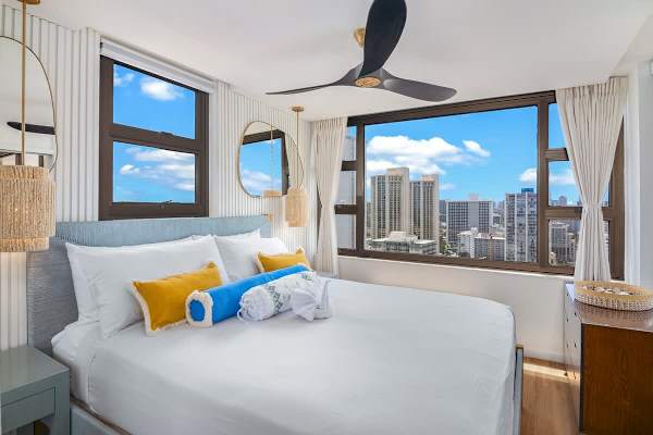 Your bedroom with king-size bed, ceiling fan, and beautiful ocean and city views.