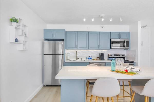 Fully equipped kitchen with full-size appliances, and dining area with 4 bar stools.