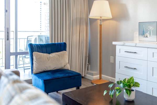 In the living area, it has a blue accent chair and a floor lamp.