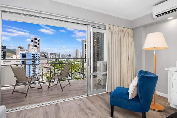 Your condo has a split-type AC, accent chair, and a view of the balcony.