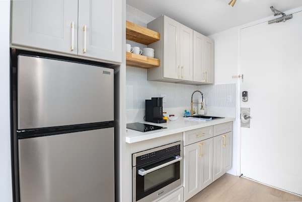 A newly renovated kitchenette with a full-size refrigerator, a 2-burner stove, and a new Keurig coffee maker.