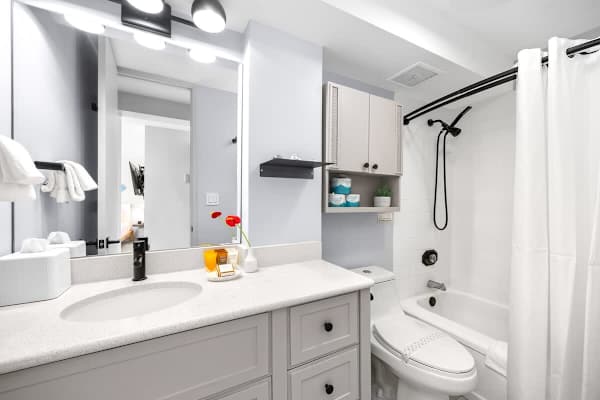 This bright and modern bathroom features a sleek vanity with ample counter space and a refreshing shower-over-tub, all designed for your comfort and ease.