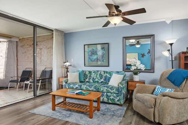Living area with pull-out sleeper sofa, coffee table, armchair, ceiling fan, and a split AC.