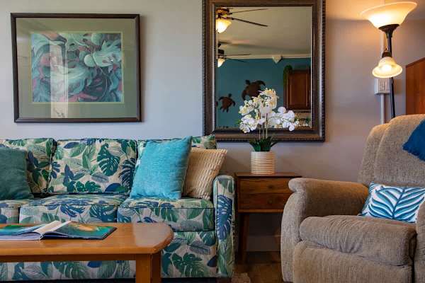 Living area with pull-out sleeper sofa, coffee table, armchair, ceiling fan, and a split AC.