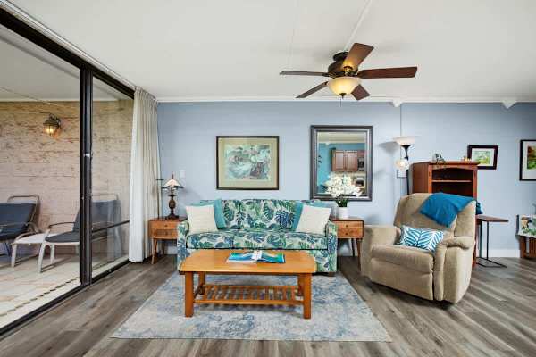 Living area with pull-out sleeper sofa, coffee table, armchair, ceiling fan, and a split AC.