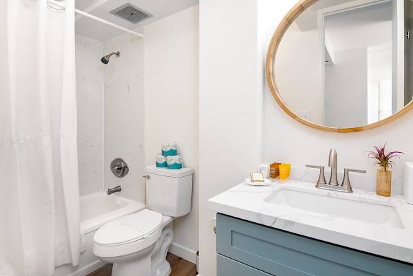 Start your day fresh in the newly renovated bathroom featuring a chic marble-style vanity, a modern round mirror, and a sparkling tub/shower combo.