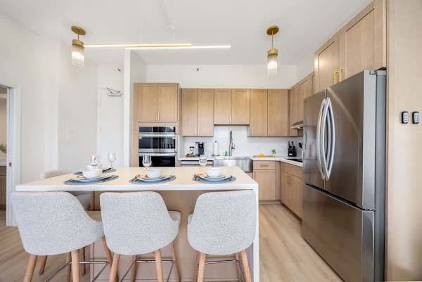Kitchen island w/ seating & stainless steel fridge in a bright, open layout
