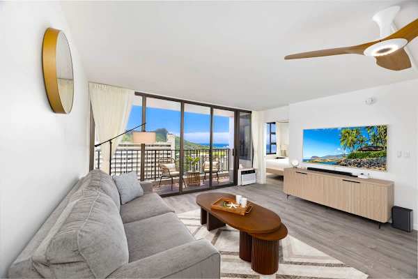 The living room has a pull-out sleeper sofa, coffee table, 65" Smart TV and ceiling fan