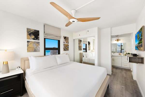 Bedroom with King-sized bed, 55" Smart TV, ceiling fan, and access to the bathroom