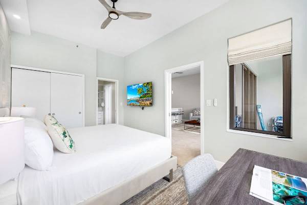 Bedroom with king-sized bed, working station by the window, TV, ceiling fan, and access to the bathroom