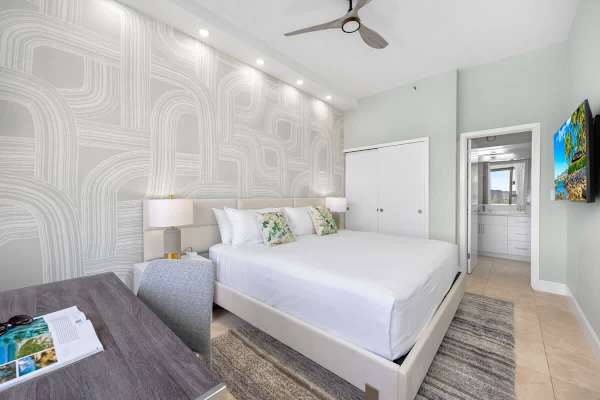 Bedroom with king-sized bed, working station by the window, TV, ceiling fan, and access to the bathroom