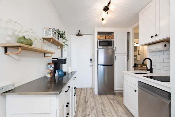 Modern and fully equipped kitchenette with sleek appliances and stylish open shelving!