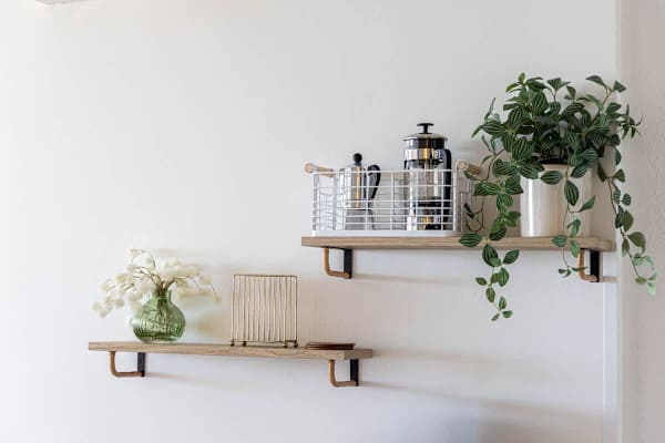 Start your day right with a dedicated coffee setup on this stylish shelf, complete with a French press and Moka pot, accented by a decorative potted plant!