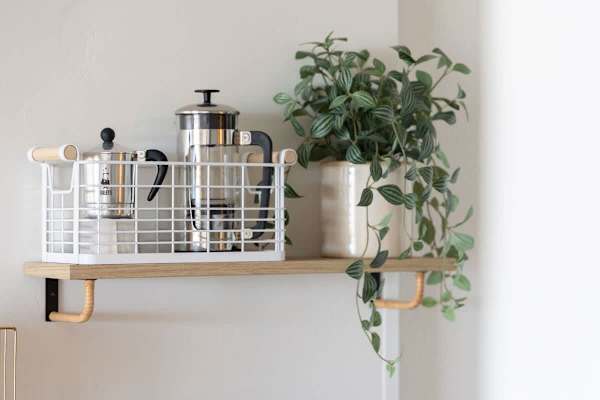 Start your day right with a dedicated coffee setup on this stylish shelf, complete with a French press and Moka pot, accented by a decorative potted plant!