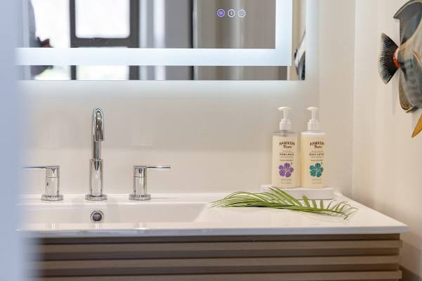 Indulge in this luxurious and modern bathroom, featuring a sleek slatted vanity with a backlit mirror, and a starter supply of toiletries for a truly refreshing experience