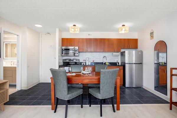 Dine and prepare meals with ease in this well-appointed kitchen and dining area, featuring modern appliances, a stylish table with seating for four, and convenient access to the adjacent bathroom