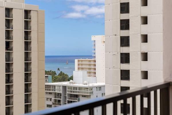 Glimpse of the sparkling ocean from the balcony framed by city views, offering a refreshing connection to the beautiful surroundings