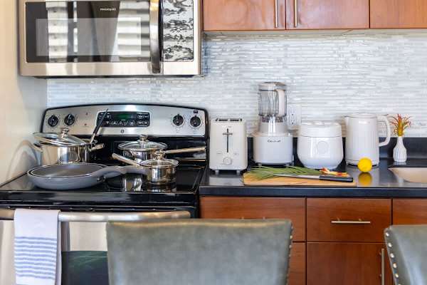 Whip up delicious meals in this fully equipped kitchen, featuring modern stainless steel appliances including a Frigidaire microwave, GE electric range, and essential Cuisinart small appliances