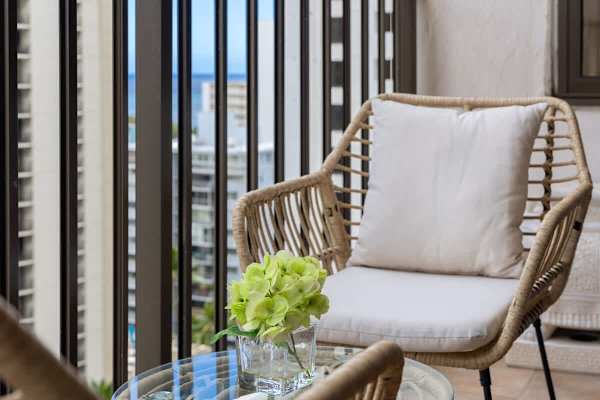 Relax in style on the balcony, featuring comfortable seating and a charming table, all set against a backdrop of stunning city and distant ocean views.