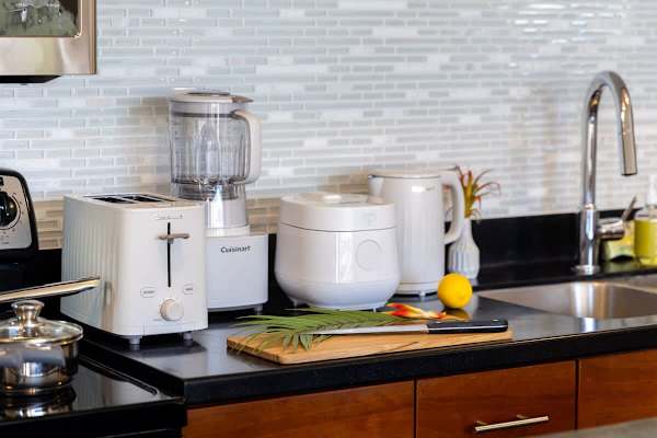 Effortlessly prepare snacks and meals with a suite of essential Cuisinart appliances, including a toaster, blender, and rice cooker, complemented by a sleek sink area for your convenience