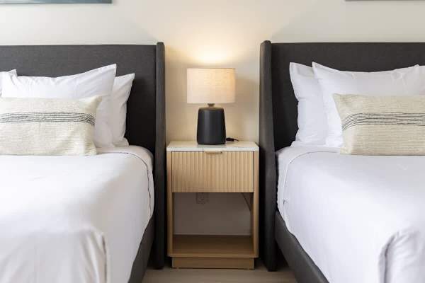 Relax in the bedroom, which features 2 queen-size beds, a modern nightstand, and a lamp, ensuring a restful and convenient stay
