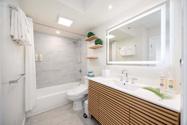 Modern bathroom complete with bathtub and shower, an elegant slatted vanity, a smart bidet toilet, and ample lighting for a refreshing experience