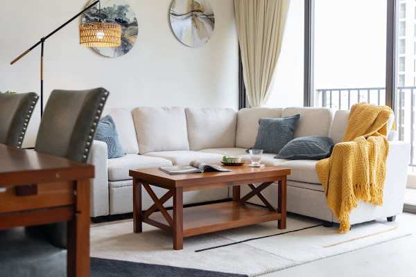 Unwind in the living area, which features a comfortable sectional sofa with plush cushions, a stylish coffee table, and soft lighting, perfect for relaxation and gathering