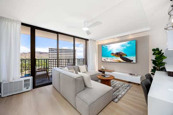 Unwind in comfort within your stylish living room, featuring a window AC, an 85" Smart TV for entertainment, and a private balcony connecting you to stunning island views.