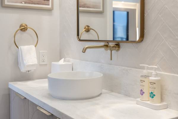 Indulge in refined comfort at your spa-inspired vanity, featuring a sleek vessel sink and elegant gold fixtures for a touch of luxury.