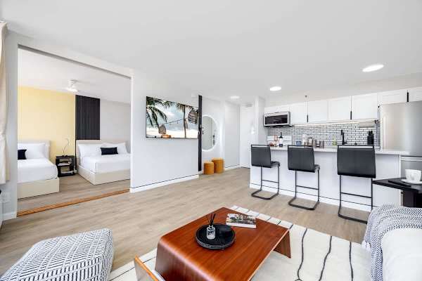 Experience the spacious elegance of an open-concept living area, seamlessly connecting a modern kitchen, living area, and inviting bedroom.