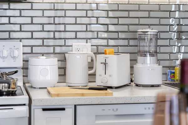 Start your day right with a well-appointed kitchen countertop, featuring a sleek kettle, rice cooker, toaster, and blender for your convenience.