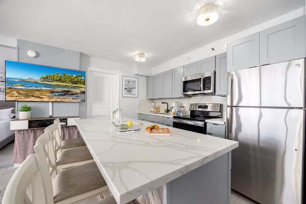 This modern kitchen is a chef's delight, featuring a spacious island with seating and a large TV for entertainment while you cook.