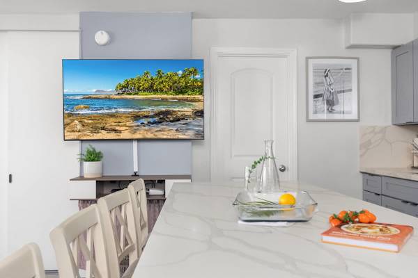 This bright kitchen features a generous island perfect for meal prep or casual dining, all while enjoying entertainment on the nearby flat-screen.