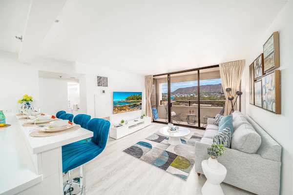 Discover the perfect blend of style and comfort in this open-concept living space, featuring a modern kitchen with a breakfast bar, a 65" smart TV, and stunning Diamond Head views from the adjoining balcony.
