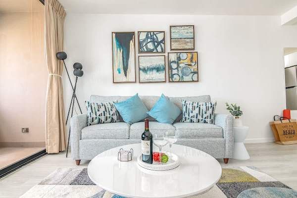 The stylish living room features a comfortable pull-out sleeper sofa, perfect for additional guests, all set against a backdrop of captivating artwork and ample natural light.