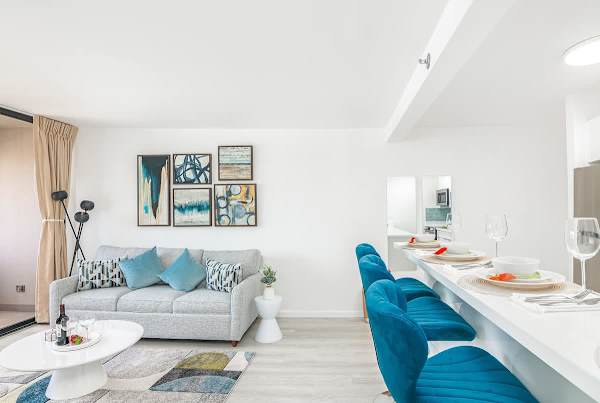 Step into this bright and inviting living space, where the stylish sofa and captivating artwork create a perfect atmosphere for relaxation, seamlessly flowing into the modern breakfast bar with its vibrant seating.