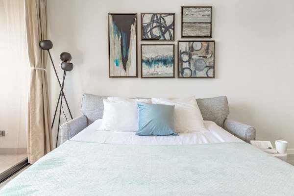 The stylish living room features a comfortable pull-out sleeper sofa, perfect for additional guests, all set against a backdrop of captivating artwork and ample natural light.
