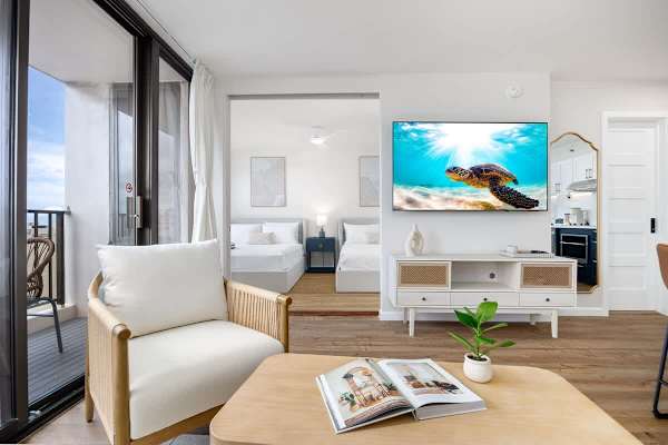 This inviting living space offers comfortable seating, a 65" Smart TV, and seamless access to a private balcony and a cozy bedroom area.