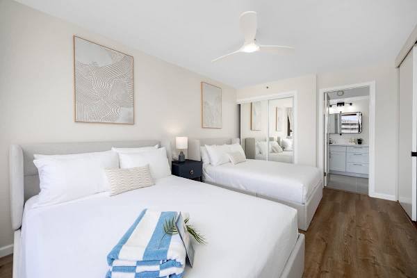 The bedroom features a queen and a full-size bed, a 50" flat-screen TV, a ceiling fan, a closet, and easy access to the bathroom.