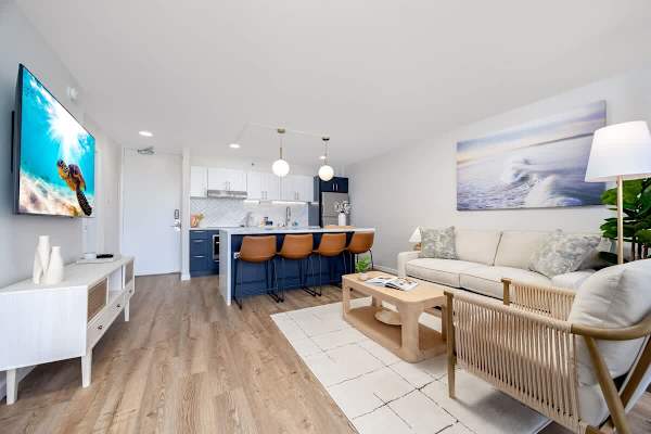 This spacious open-concept living area combines a comfortable living area with a modern kitchen and breakfast bar, perfect for relaxation and entertaining.