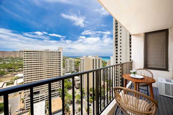 Relax and soak in the expansive city, mountain, and partial ocean views from this inviting balcony, complete with comfortable seating.