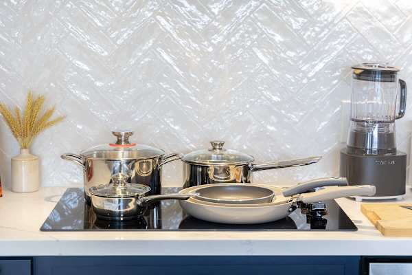 Prepare gourmet meals with ease using this well-equipped kitchen's full set of modern pots, pans, and essential appliances on a sleek induction cooktop.