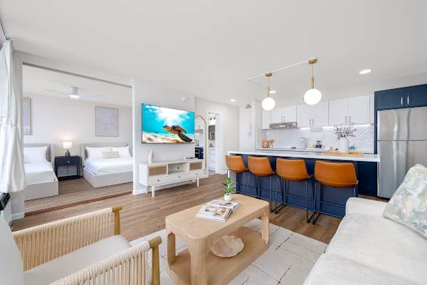 This modern open-concept living space seamlessly connects a cozy living area with a fully equipped kitchen and dining area, perfect for relaxed living and entertaining.