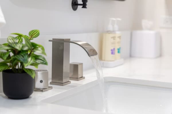 Experience modern elegance with this sleek waterfall faucet in the bathroom.
