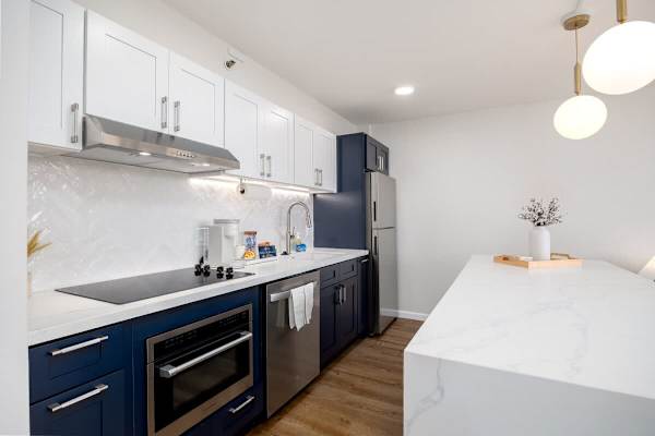 This stylish and fully-equipped kitchen boasts modern appliances, ample counter space, and chic blue and white cabinetry.